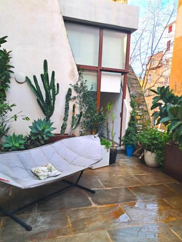 un patio avec des plantes et un hamac en face d'un bâtiment dans l'établissement Chambres de charme au coeur de la citadelle de BASTIA, à Bastia