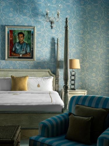 a bedroom with a bed and a chair and a painting at Rajmahal Palace RAAS in Jaipur