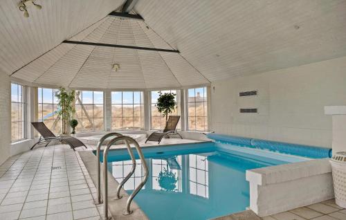 ein großer Pool mit Stühlen und einem Sonnenschirm in der Unterkunft Pet Friendly Home In Ringkøbing in Nørre Lyngvig