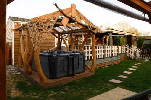 a wooden gazebo with a trash can in a yard at Bespoke Holiday Home With Private Pool And Hot Tub, Sleeps 8 Ref 34073P in Kings Lynn