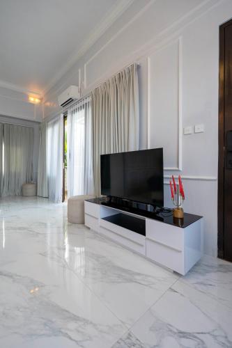 a white living room with a television and a couch at Place of Power in Blahbatu