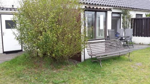 a wooden bench sitting next to a bush next to a house at Amalia in Nes
