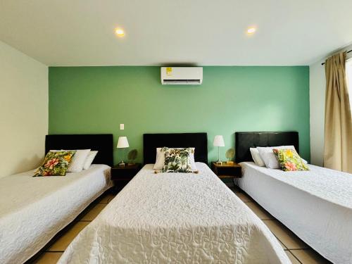two beds in a room with green walls at TURULEKA Hostel in Roldanillo