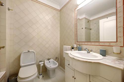 a bathroom with a toilet and a sink and a mirror at Sol do Atlântico in Portimão