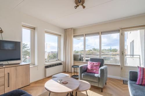 a living room with a tv and a couch and a chair at Appartementencomplex Juliana 36 in De Koog