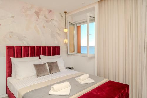 a bedroom with a large bed with a red headboard at Kolovare Luxury Rooms in Zadar