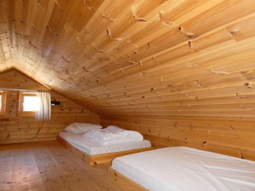 two beds in a room with a wooden ceiling at Helligvær Kystopplevelser AS in Helligvær