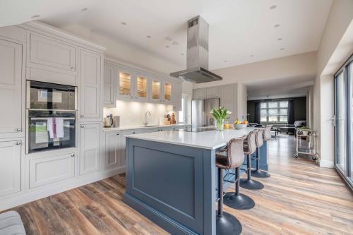 a kitchen with white cabinets and a large island with stools at FAMILY FRIENDLY ESCAPE IN ETON, COUNTRYSIDE VIEWS with Hot Tub - By Tempstay in Eton