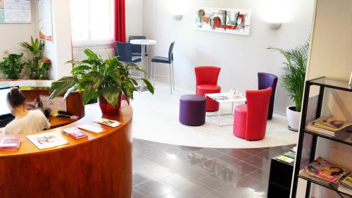 a woman sitting at a desk in a room with chairs at Hôtel Robinson in Auch