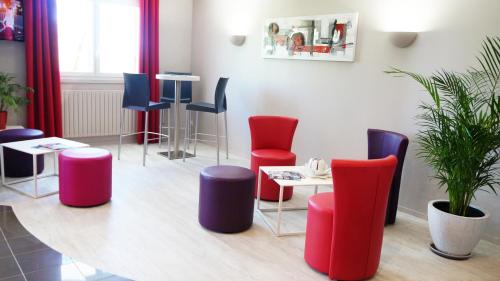 a waiting room with colorful chairs and a table at Hôtel Robinson in Auch