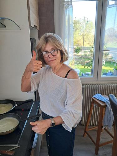 a woman giving a thumbs up in a kitchen at La Maison in Mirebeau-sur-Bèze