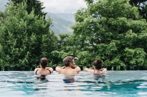 a man and two girls in a swimming pool at Haven Mountain Retreat in Sankt Johann im Pongau