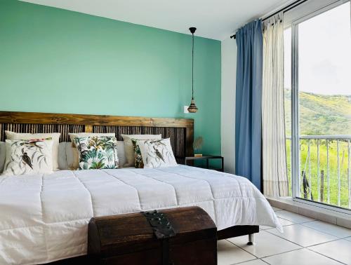 a bedroom with a large bed and a large window at TURULEKA Hostel in Roldanillo