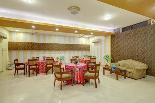 a dining room with tables and chairs and a couch at Hotel B Stays in Gurgaon
