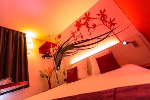 a bedroom with a bed with a flower on it at Hotel Inn Design Sedan in Sedan