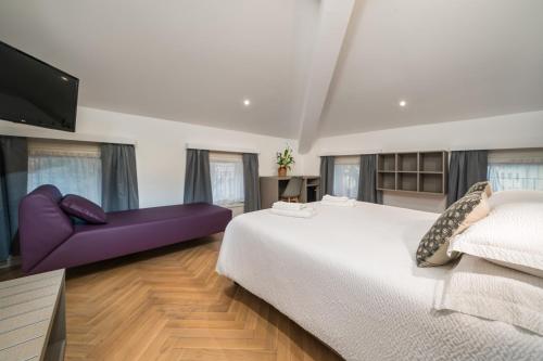 a bedroom with a large bed and a purple couch at B&B PIEDICASTELLO in Trento