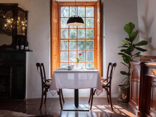a dining room with a table and a window at Adara Palmiet Valley Luxurious Boutique Farm Hotel in Paarl