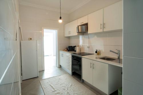 a kitchen with white cabinets and a white refrigerator at Palmela 33 - in the Heart of Historic Center in Palmela
