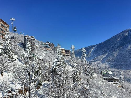 a snow covered mountain with trees and buildings on it at Hotel Seven Hills Manali in Manāli