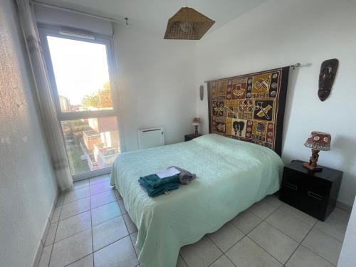 - une chambre avec un lit doté d'un couvre-lit vert et d'une fenêtre dans l'établissement Bel appartement,2 chambres, clim, vue, parking, à Lattes