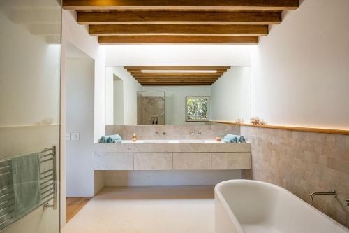 a bathroom with a tub and a large mirror at Noordhoek Sunset Villa in Flat Acres