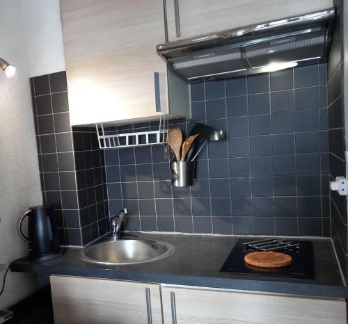 une petite cuisine avec un évier et une cuisinière dans l'établissement Pied à terre, séjour idyllique face à la mer classé 2 étoiles, à Sanary-sur-Mer