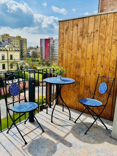 two tables and chairs on a patio with a fence at Apartmán CORA in Jaroměř