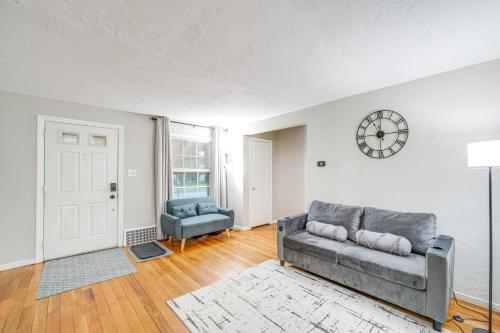 a living room with a couch and a clock on the wall at 2 Mi to Lake Erie Home with Yard in Euclid! in Euclid