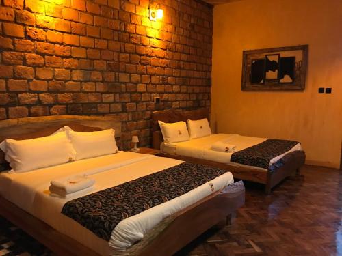two beds in a room with a brick wall at Masaka Cultural Resort in Masaka