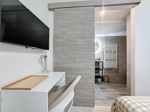 a bedroom with a white desk and a tv on a wall at Les Vignes 3 Chambres avec Salle de bain privative in Anse