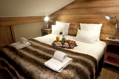a hotel room with a bed with towels and a tray of food at Chamois d'Or Hotel in Les Gets