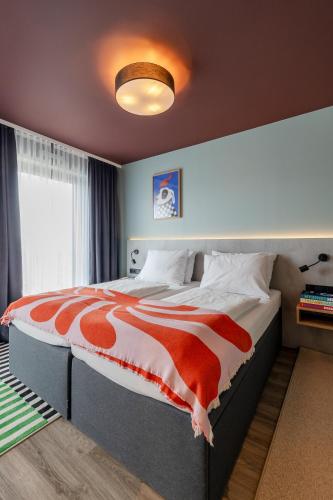 a bedroom with a large bed with a red and white comforter at kalm stay - munich east in Munich