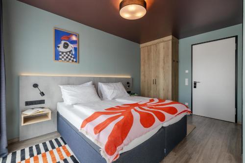 a bedroom with a bed with an orange and white comforter at kalm stay - munich east in Munich