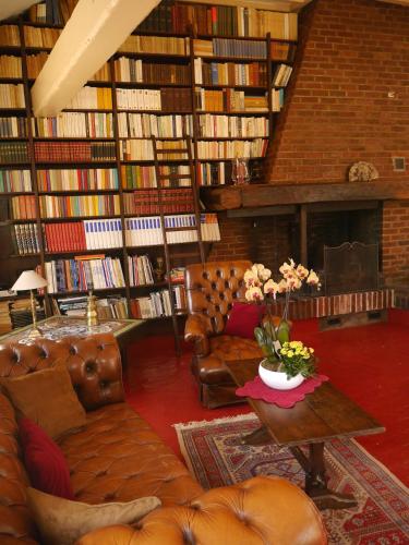a library with a couch and a table with flowers at Le Puits D'Angle in Thibivillers