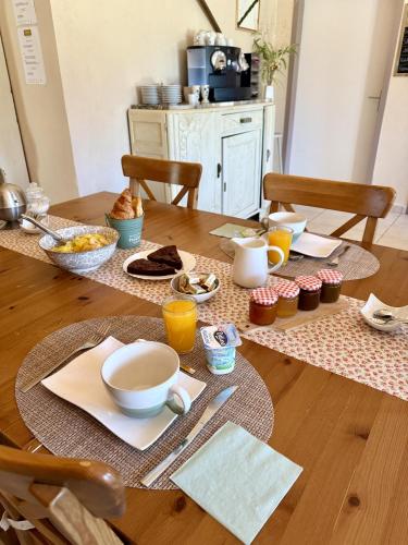 a table with breakfast foods and orange juice on it at Chambres d'Hôtes Aux Ecuries du Chateau in Contremoulins