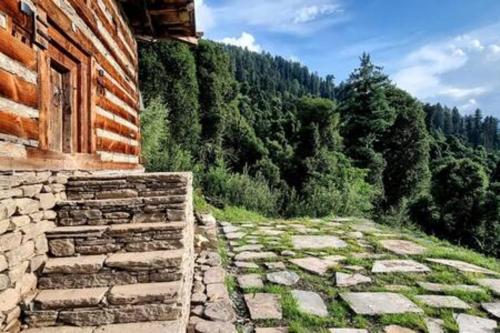 a stone path next to a building with a forest at ArtVillage Naggar - Entire Katkuni Villa in Nagar