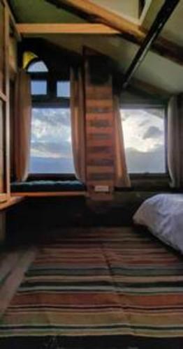 a bedroom with a bed and a large window at ArtVillage Naggar - Entire Katkuni Villa in Nagar