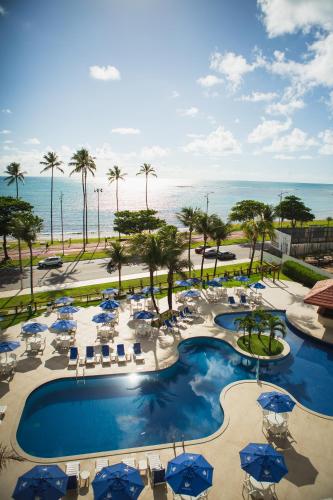 an aerial view of a resort pool with chairs and umbrellas at Maceió Atlantic Suites in Maceió