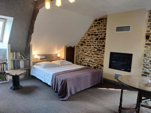 ein Schlafzimmer mit einem Bett und einer Steinwand in der Unterkunft Gîtes de la Croix du Bourg in Le Mesnil-Ozenne
