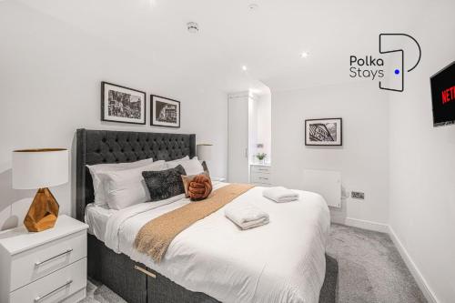 a white bedroom with a large bed with a lamp at The Stables, Chester - Luxury Apartments by PolkaStays in Chester