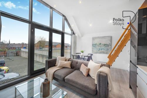 a living room with a couch and large windows at The Stables, Chester - Luxury Apartments by PolkaStays in Chester