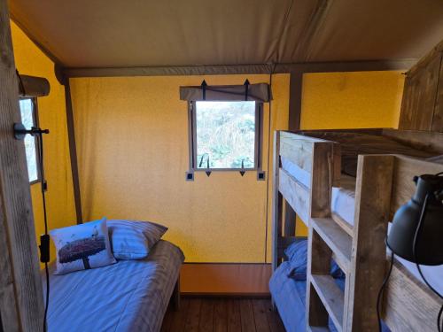 a bedroom with two bunk beds and a window at De Hazelaarshof Luxe glampingtent bij natuurgebied De Millingerwaard in Kekerdom