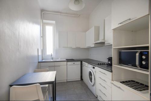 - une cuisine blanche avec une table et un four micro-ondes dans l'établissement Cocon Urbain lumineux et hyper central pour 1 à 4 personnes, à Marseille