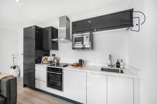 a kitchen with white cabinets and black appliances at The Stables, Chester - Luxury Apartments by PolkaStays in Chester