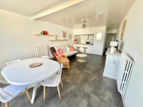 un salon avec une table et des chaises blanches dans l'établissement Appartement lumineux sur plage avec piscine et parking - FR-1-716-81, au Grau-du-Roi