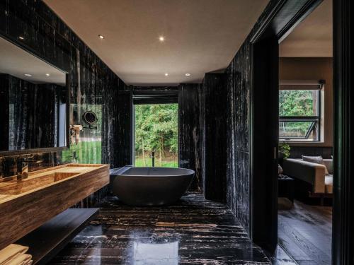 uma casa de banho preta com uma banheira e uma grande janela em 景德镇行山世外东篱院民宿 em Xianghu