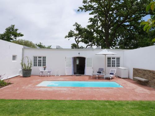 a white house with a swimming pool in the yard at Adara Palmiet Valley Luxurious Boutique Farm Hotel in Paarl