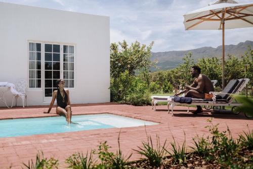a man and a woman sitting in a swimming pool at Adara Palmiet Valley Luxurious Boutique Farm Hotel in Paarl