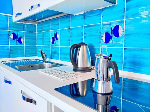 a blue tiled kitchen with a sink and a tea kettle at Appartamento con piscina e vista mozzafiato in Cascabraga