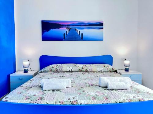 a bedroom with a bed with a blue headboard and two lamps at Appartamento con piscina e vista mozzafiato in Cascabraga